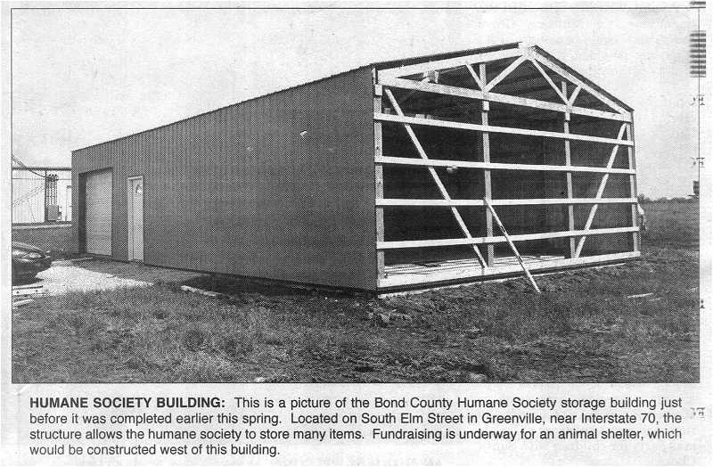 newspaper photo with caption, storage building/garage under construction just before completion.