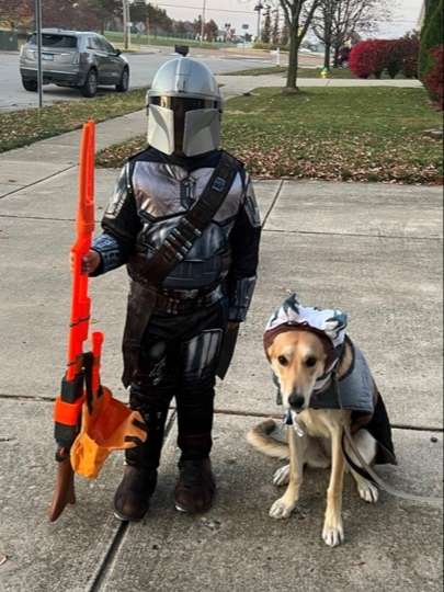 brown shepherd mix dog in costume beside boy in costume ready for Halloween fun
